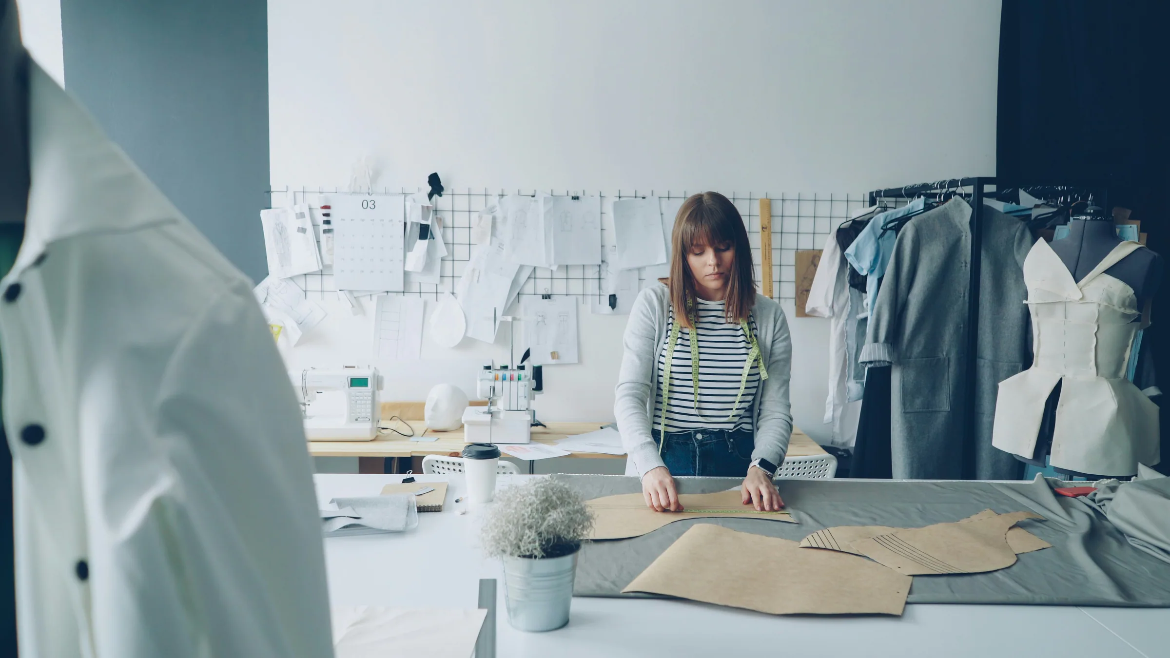 Fashion designer measuring paper templates and fabric in a studio